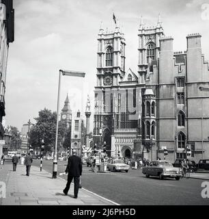 Ende 1950s, historische Great Smith Street in der City of Westminster, London, England, Großbritannien, zeigt allgemeine Aktivität und die berühmte Kirche, Westminster Abbey. Der Elizabeth Tower, einer der drei Türme des Palace of Westminster und besser bekannt als Big Ben, ist in der Ferne zu sehen. Stockfoto