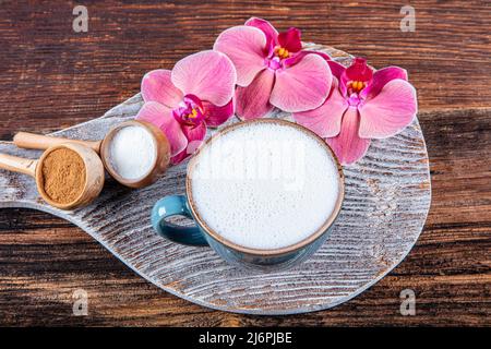 Nahaufnahme einer weißen Tasse milchig heißen Saleps auf einem Holzhintergrund. Tasse Salep milchig traditionellen heißen Getränk der Türkei mit Zimt in einer Porcela serviert Stockfoto