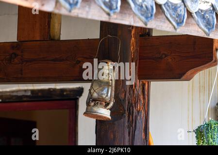 Nahaufnahme einer Retro-Petroleumlampe, die auf einem Holzspieß hängt Stockfoto