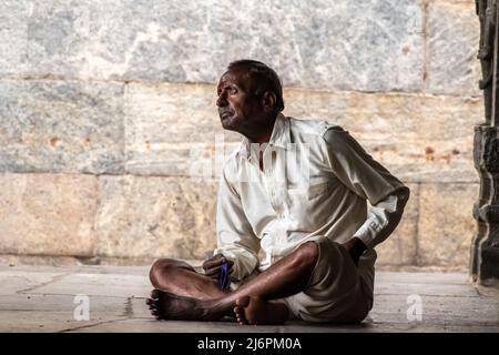 Vellore, Tamil Nadu, Indien - Septembermber 2018: Ein ehrliches Porträt eines Indianers, der mit gekreuzten Beinen sitzt und nachdenklich auf den Steinboden eines Stockfoto