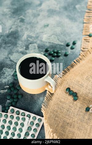 Spirulina Pillen Tabletten Packung und einen Becher mit einem Getränk Stockfoto