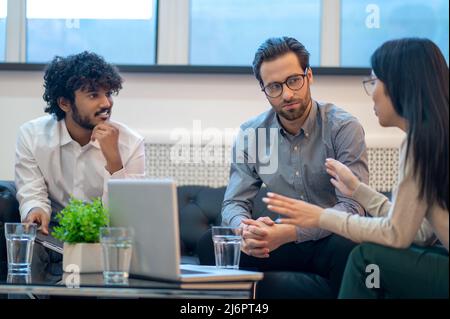 Drei Mitarbeiter des Unternehmens halten eine Gruppendiskussion ab Stockfoto
