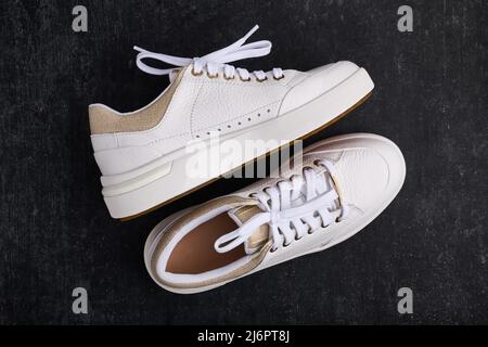 Sportliche Damenschuhe, Leder-Sneakers auf grauem Hintergrund, flaches Lay Stockfoto