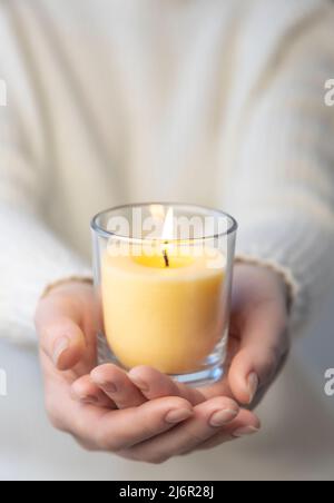 Eine Kerze brennt in den Handflächen einer Frau. Kerzenhitze. Stockfoto