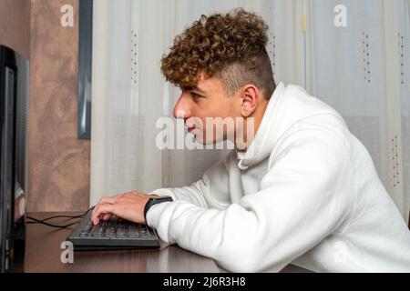 Männlicher Programmierer, der aufgrund der Umstrukturierung des Unternehmens im Speisesaal seines Hauses an einem Desktop-Computer arbeitet Stockfoto