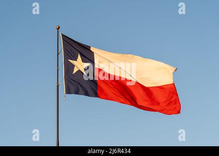 Flagge von Texas winkt im Wind mit blauem Himmel im Hintergrund. Texas ist ein Staat in der Region South Central der Vereinigten Staaten. Stockfoto