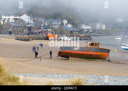 Menschen am Strand von Barmouth mit tiefem Wolkennebel über der Stadt Stockfoto