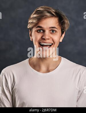 Lustige junge gut aussehende Kerl auf grauem Hintergrund. Stockfoto