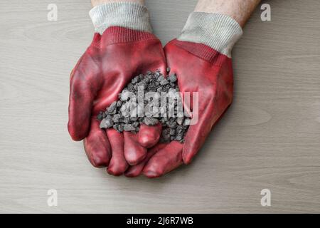 Eine Handvoll Ölsand, der aus den Ölsand-Lagerstätten in Athabasca in der Nähe von Fort McMurray, Alberta, Kanada, gefördert wird. Stockfoto