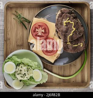 Offenes Rinderbraten und Tomatenbrot mit Senf- und Kartoffelsalat und Eierscheiben auf einem Kopfsalat. Stockfoto