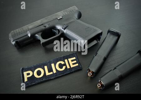 9-mm-Pistole mit zwei voll beladenen Zeitschriften und Polizei-Klettabzeichen auf schwarzem Holzschreibtisch Stockfoto