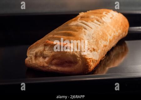 Ein gebackenes hausgemachtes Brötchen mit Apfelmarmelade im Elektroofen: Nahaufnahme Stockfoto