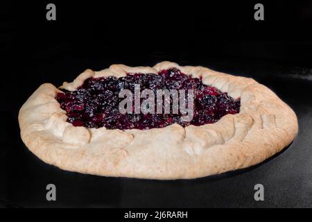 Gebackene hausgemachte Galette, offener Kuchen mit Kirschbäcken im Elektroofen Stockfoto