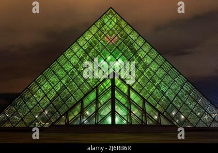 Die Glaspyramide des musée du Louvre ist nachts mit grünen Lichtern beleuchtet. Stockfoto