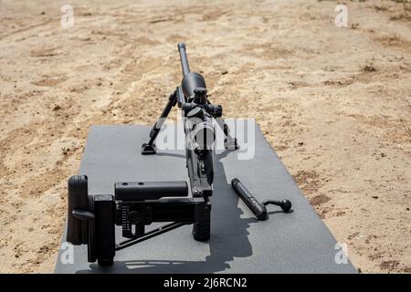 Modernes Scharfschützengewehr auf Zweibeinern. Abgesetzte Scharfschützenwaffe in Kampfposition. Heller Hintergrund. Stockfoto