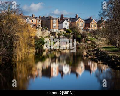 Häuser spiegeln sich im stillen Wasser des Flusses Wansbeck in Morpeth, Northumberland, Großbritannien Stockfoto