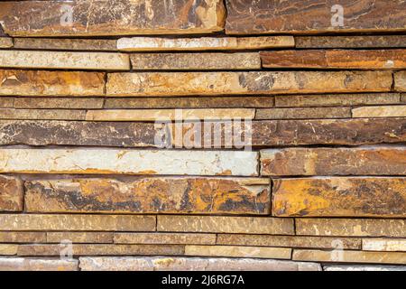 Trocken gestapelte Steinwand aus großen Platten mit buntem Sandstein Hintergrund Stockfoto