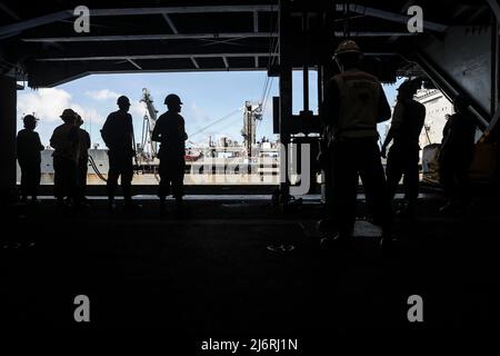 PHILIPPINISCHE SEE (30. April 2022) Matrosen stehen bereit, um Fracht in der Hangarbucht an Bord des Flugzeugträgers USS Abraham Lincoln (CVN 72) der Nimitz-Klasse während einer Auffüllung auf See mit dem Militär-Sealift-Kommando-Flottennachfüller USNS Tippecanoe (T-AO 199) zu transportieren. Die Abraham Lincoln Strike Group befindet sich im geplanten Einsatzgebiet der US-Flotte für 7., um die Interoperabilität durch Allianzen und Partnerschaften zu verbessern und gleichzeitig als reaktionsfähige Truppe zur Unterstützung einer freien und offenen Region im Indo-Pazifik-Raum zu dienen. (USA Navy Foto von Mass Communication Specialist 3. Klasse Thaddeus Berry Stockfoto