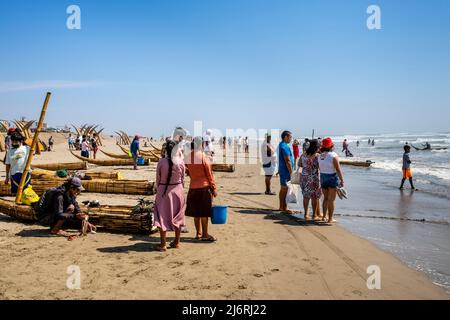 Die Einheimischen Warten Am Strand Auf Die Rückkehr Der Fischer In Ihren Traditionellen Caballitos De Totora (Schilfboote), Pimentel Beach, Chiclayo, Peru. Stockfoto