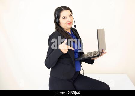 Nette und erfolgreiche Geschäftsführerin, die in schwarzem Anzug und blauem Bluse arbeitet, hart an ihrem Laptop auf weißem Hintergrund Stockfoto