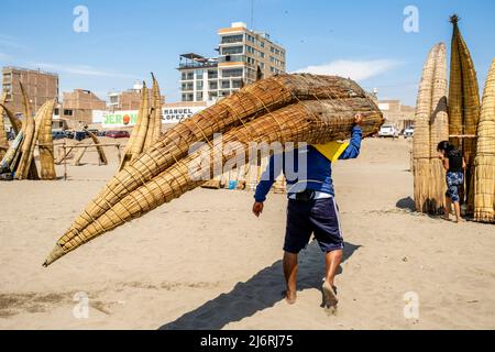 Ein Fischer mit Einem Caballito de Totoro (traditionelles Schilfboot), Pimentel Beach, Chiclayo, Provinz Chiclayo, Peru. Stockfoto