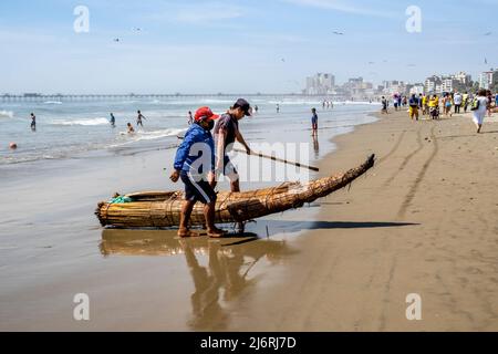 Fischer, die ein Caballito de Totoro (traditionelles Schilfboot), den Pimentel-Strand, Chiclayo, Provinz Chiclayo, Peru, an Land bringen. Stockfoto