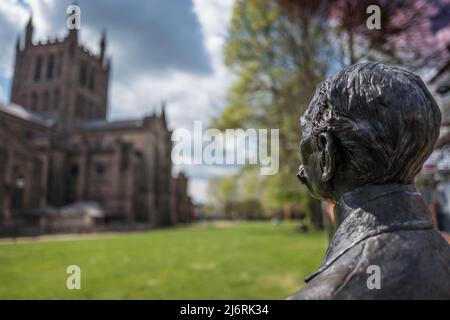 Bronzestatue von Edward Elgar, der sich auf dem Gelände der Hereford Cathedral, Hereford, Herefordshire, England, an einem Fahrrad lehnt. Stockfoto
