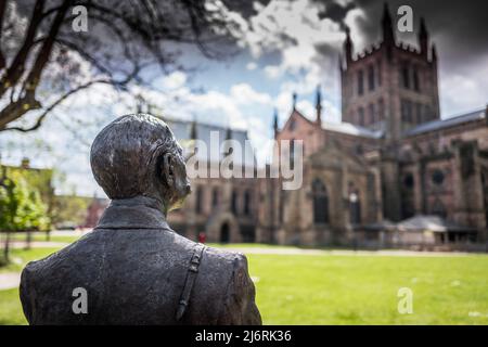 Bronzestatue von Edward Elgar, der sich auf dem Gelände der Hereford Cathedral, Hereford, Herefordshire, England, an einem Fahrrad lehnt. Stockfoto