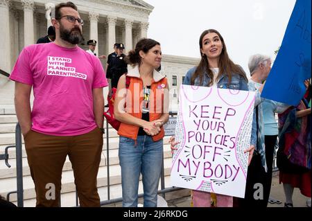 Ein Protestler in einem Hemd mit der Aufschrift „Ich stehe mit geplanter Elternschaft“ steht neben einer Frau, die ein Plakat mit der Aufschrift „Keep your Policies off my body“ während einer Abtreibungsdemonstration vor dem Obersten Gerichtshof hält. Stockfoto