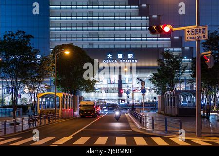 Osaka, Japan - 1. Mai 2022: Ein Motorrad nähert sich nachts der Ampel vor dem JR-Bahnhof Osaka Stockfoto