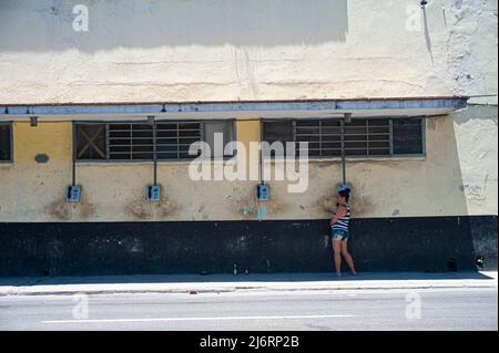 Frau spricht in Havanna, Kuba, über ein altes, veraltetes öffentliches Telefon. Stockfoto