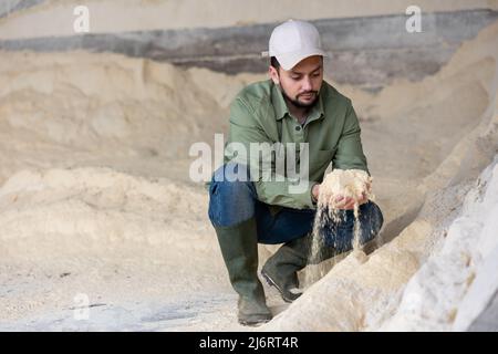 Bauer hockt auf einem Haufen Maismehl Stockfoto