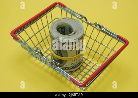 In einen Schlauch gerollte Dollars liegen in einem Einkaufskorb. Stockfoto