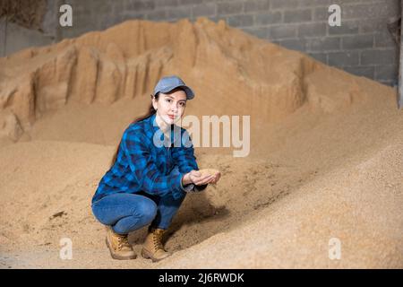 Eine agronomische Frau, die an einem Haufen Sojabohnenschalen hockt Stockfoto