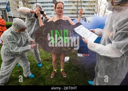 Die in blauem Rauch gestrahlte Demonstratorin der weiblichen Ozeanaufstand wird von den Ermittlern der Klimakriminalität während des Global LNG Bankering Summit beschuldigt, den Planeten verschmutzt zu haben. Während des Global LNG Bankering Summit 2022 stellt die Industrie fest, dass LNG oder Flüssigerd-Erdgas im Vergleich zu schwerem Heizöl der sauberste verfügbare Schiffskraftstoff ist. LNG hat deutlich geringere Emissionen von CO2 und fast nicht vorhandene Partikelemissionen und ist eine sichere Technologie, die einen höheren Energiegehalt und niedrigere Betriebskosten bietet. Ziel der 3-tägigen Konferenz ist es, den Start von Flüssig-Erdgas (LNG) in der Schifffahrt an zu initiieren Stockfoto