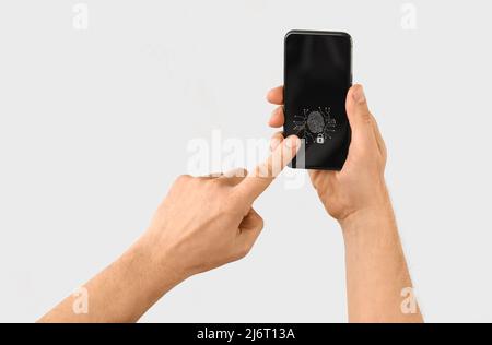 Mann mit Smartphone, der Fingerabdruckscanner verwendet, um sich auf hellem Hintergrund in ein persönliches Konto einzuloggen Stockfoto