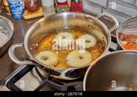 Kochen von Apfelpfannkuchen. Apfeldonut in kochendem Öl. Stockfoto