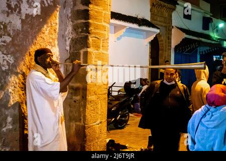 Ein Straßenkünstler spielt ein Nefar-Horn - eine marokkanische lange Trompete, die in der Aissawa-Musik verwendet wird. Av Zerktouni, Essaouira, Marokko, Nordafrika Stockfoto