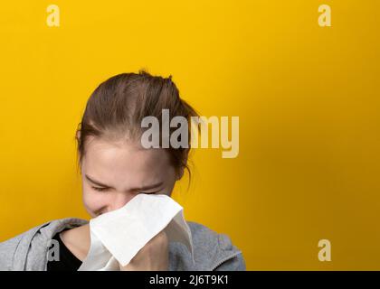 Portrait einer weinenden Dame, die Tränen mit Seidenpapier auf gelbem Hintergrund abwischt. Trauriges Mädchen oder Frauen Konzept Stockfoto