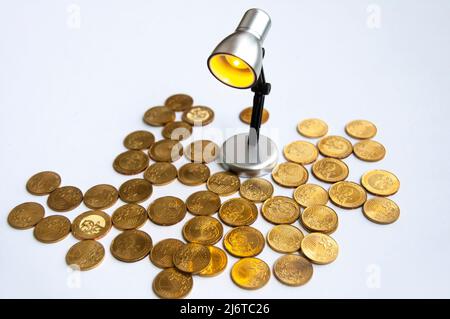 Lampe mit Goldmünzen auf weißem Hintergrund. Business- und Copy Space-Konzept Stockfoto