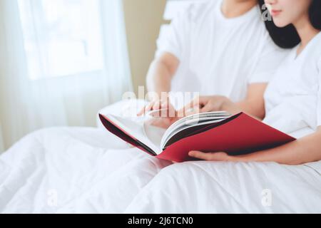 asiatische Paare planen für die Zukunft suchen Bücher, Kauf Lebensversicherung, Kauf von Häusern, Blick auf Hochzeitsfotos. Stockfoto