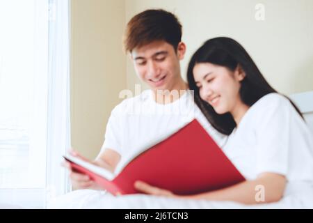 asiatische Paare planen für die Zukunft suchen Bücher, Kauf Lebensversicherung, Kauf von Häusern, Blick auf Hochzeitsfotos. Stockfoto