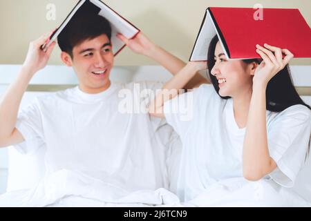 asiatische Paare planen für die Zukunft suchen Bücher, Kauf Lebensversicherung, Kauf von Häusern, Blick auf Hochzeitsfotos. Stockfoto