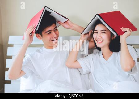 asiatische Paare planen für die Zukunft suchen Bücher, Kauf Lebensversicherung, Kauf von Häusern, Blick auf Hochzeitsfotos. Stockfoto