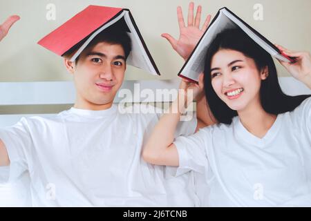 asiatische Paare planen für die Zukunft suchen Bücher, Kauf Lebensversicherung, Kauf von Häusern, Blick auf Hochzeitsfotos. Stockfoto