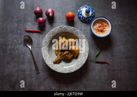 Beliebtes indisches Menü mit Hühnerfleisch in einer Schüssel und Gewürzen. Draufsicht, selektiver Fokus. Stockfoto