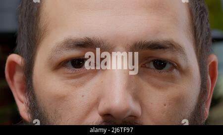 Makroaufnahme Porträt einer männlichen Person lächelnd und Blick auf die Kamera, mit weißen Zähnen und gesunde natürliche Sehkraft. Modell mit authentischem Lächeln, fröhlichem Lebensstil. Nahaufnahme. Stockfoto