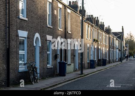 Blick auf viktorianische, gelbe Backsteinterrassenhäuser mit Mülleimern und einem Fahrrad vor der Tür, Kingston Street, Cambridge, Großbritannien Stockfoto