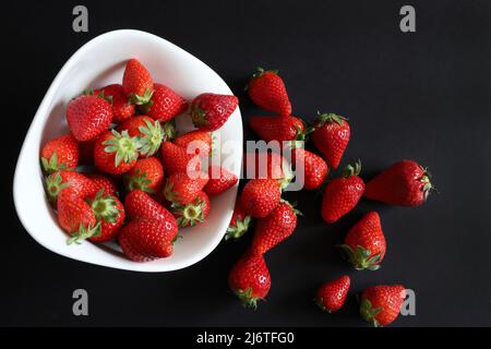 Frische Erdbeeren in einer Schüssel auf schwarzem Hintergrund. Direkt darüber. Speicherplatz kopieren. Stockfoto