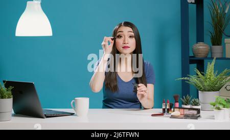 POV von Content Creator mit Mascara für Make-up-Tutorial zum Filmen Kamera, Aufnahme Schönheit Video, um Tipps für das Publikum zu geben. Asiatischer Influencer sendet Vlog mit Kosmetik. Stativaufnahme. Stockfoto